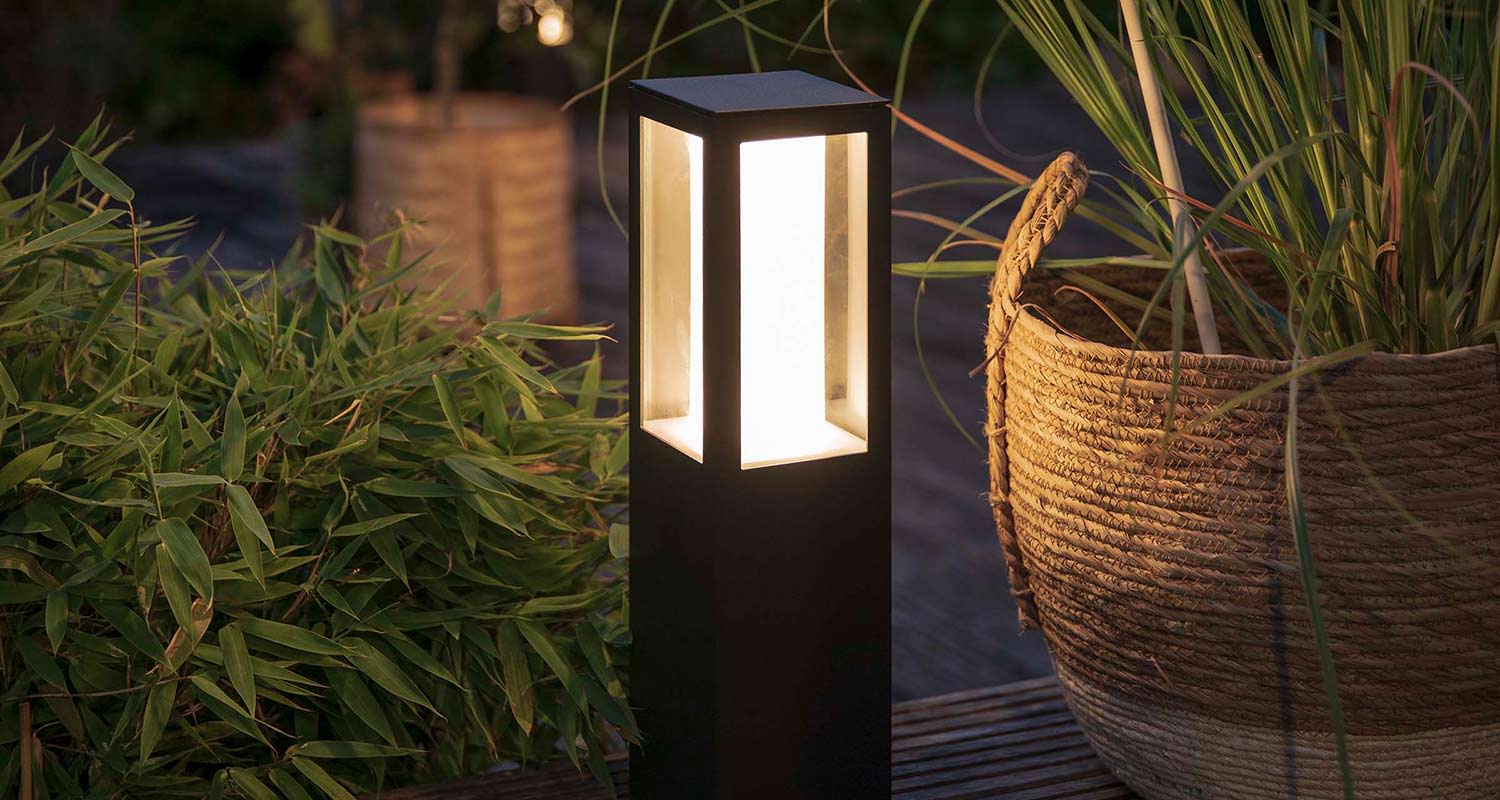 Musta ulkovalaisin loistaa lämpimästi viherkasvien ja punotun korin vieressä.