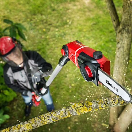 Punakypäräinen käyttäjä katkoo punamustalla teleskooppiketjusahalla keltajäkäläistä oksaa.