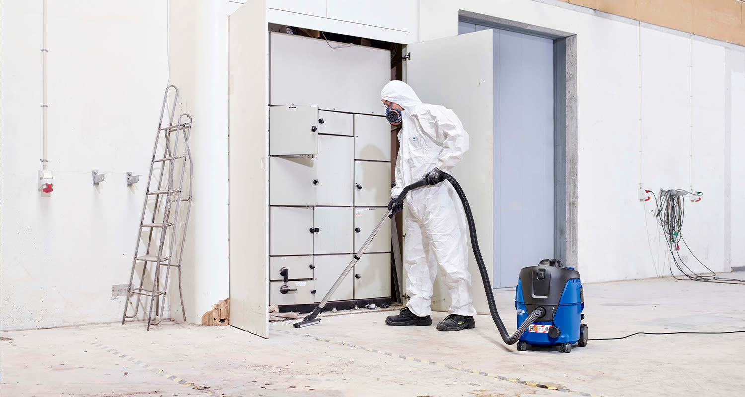 Työmies suojapuvussa ja märkä-kuivaimuri Nilfisk Aero 21-0H PC