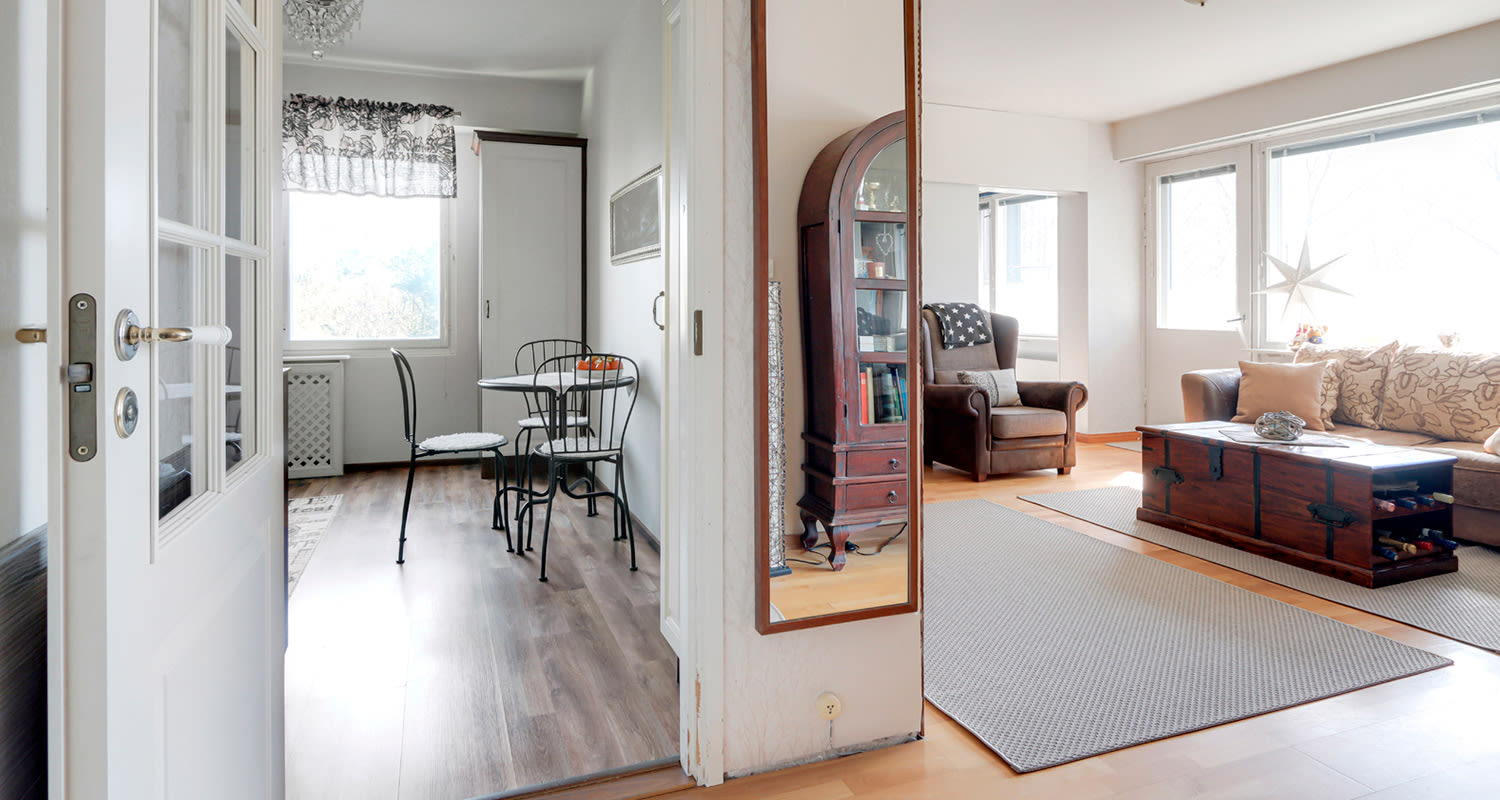 Vanha keittiö ennen remonttia keittiön ulkopuolta kuvattuna, vieressä näkyy olohuone.