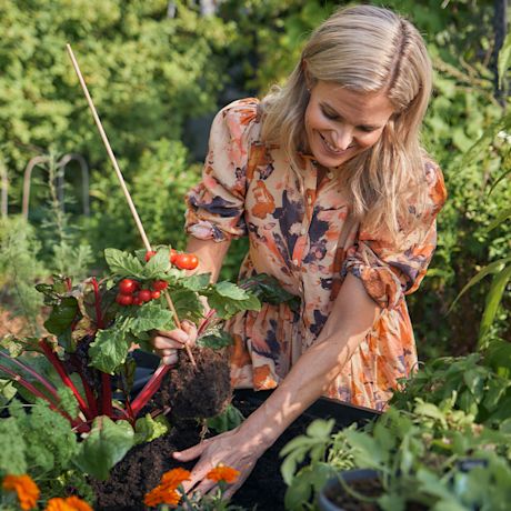 Vihreä puutarha, jossa nainen hoitaa puutarhaa.