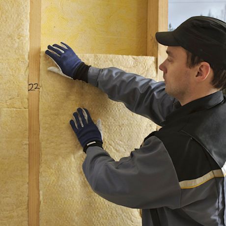 Mies asentamassa lisäeristettä omakotitalon seiniin.