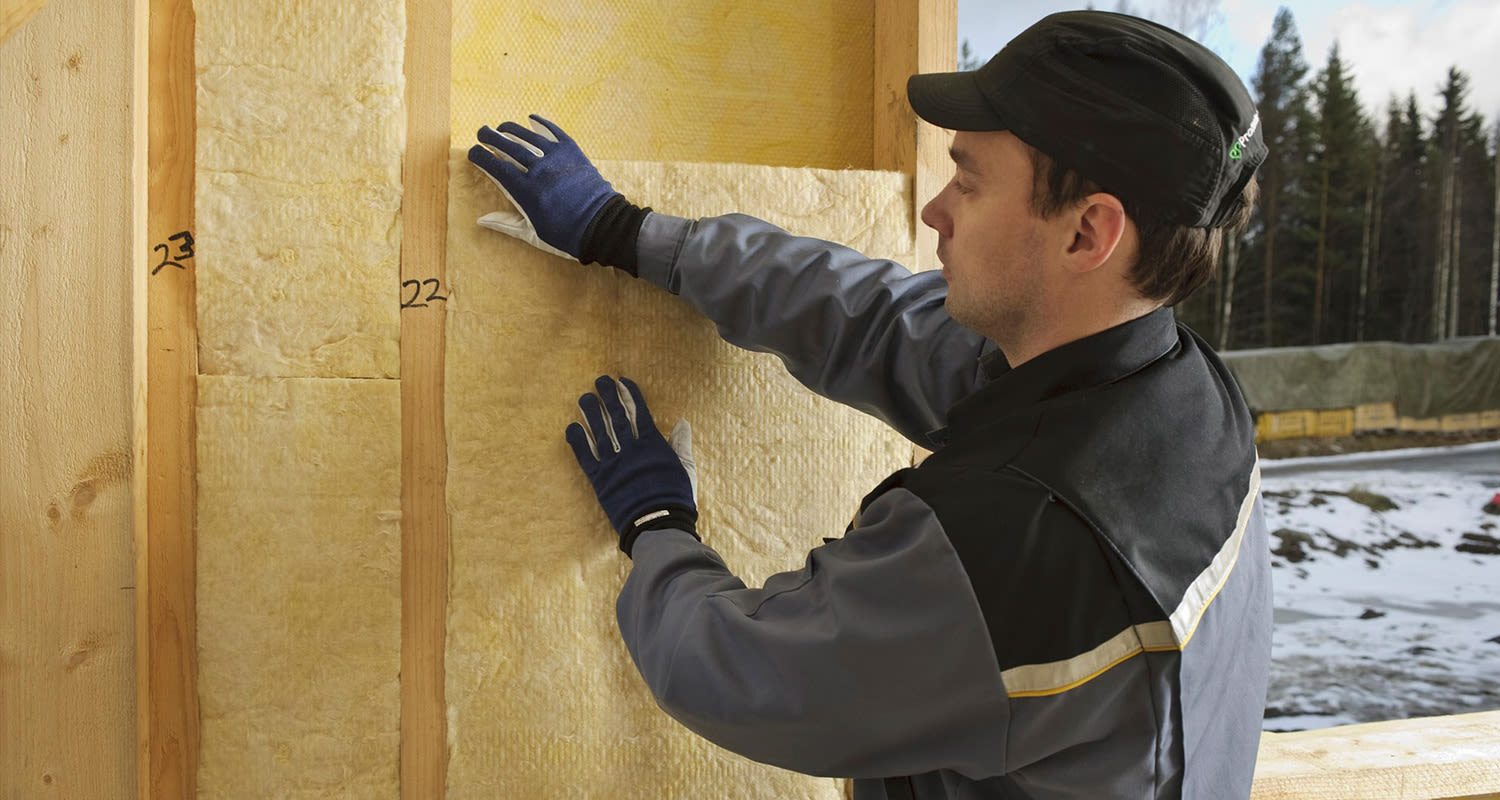 Mies asentamassa lisäeristettä omakotitalon seiniin.