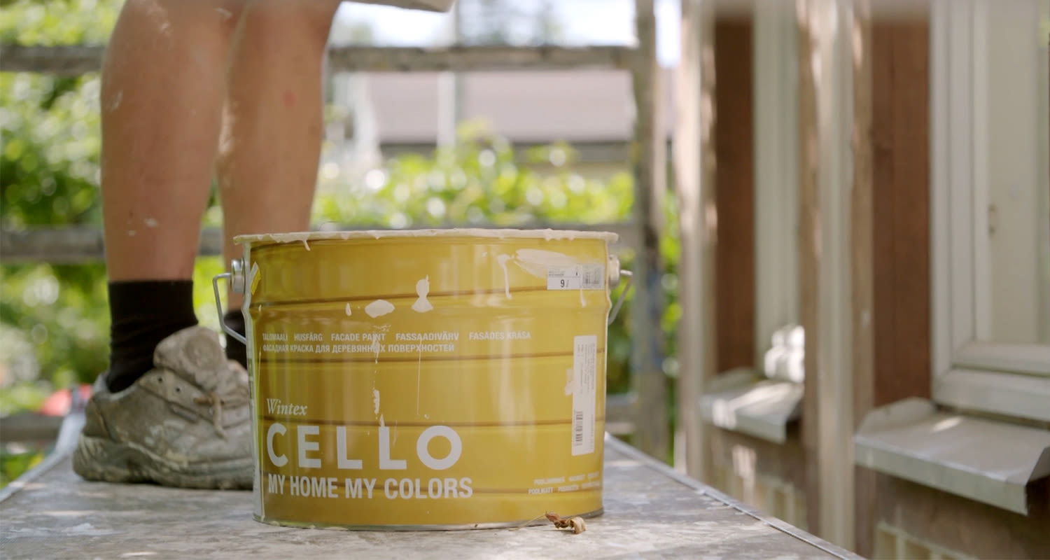 Keltainen Cello-pintamaalipurkki rakennustelineellä, maalarin maalitahraiset jalat