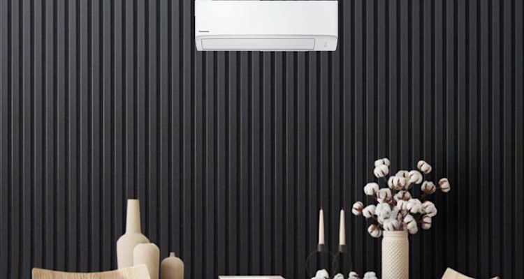 Valkoinen Panasonic-ilmastointilaite mustalla lautaseinällä, beigejä vasuja ja pumpulioksia