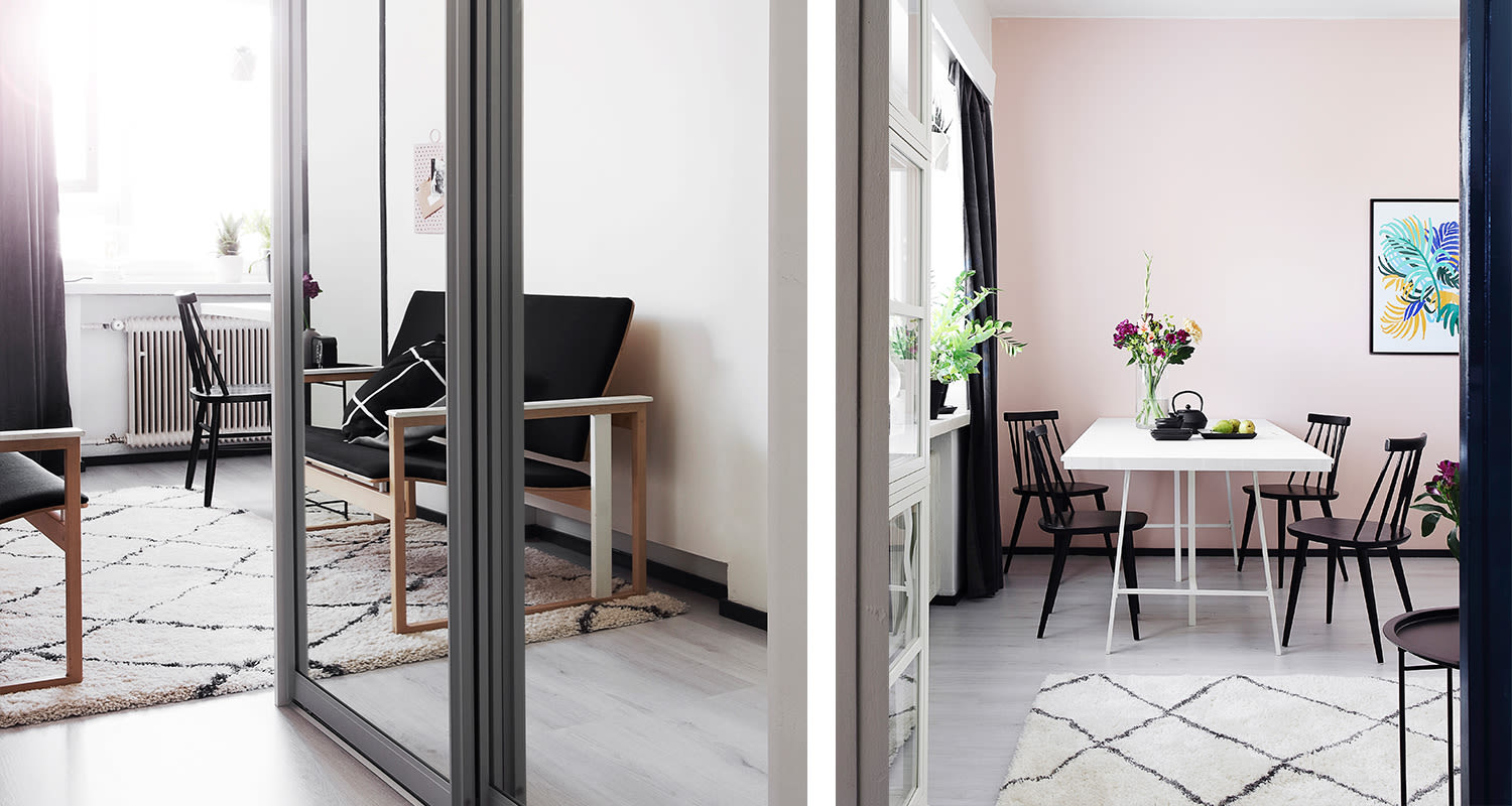 Vaalea olohuone ja vaaleanpunainen ruokailutila mustilla tuoleilla, valkoinen pöytä, kasveja.