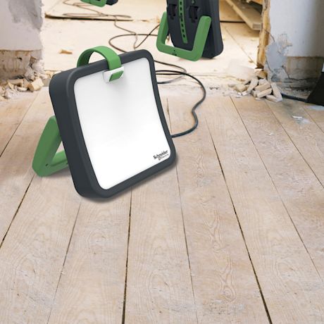 Sisärakennustyömaalla puulattialla mustavihreä Schneider Electricin LED-työvalo.