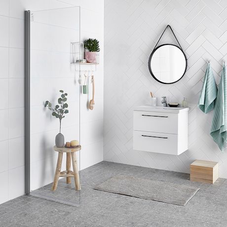 Valkoinen kylpyhuone: lasiseinäinen suihku, puinen jakkara, pyöreä peili, mintunvihreät pyyhkeet