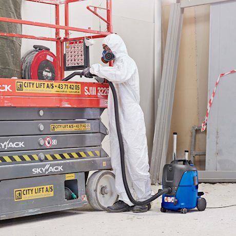 Työmies suojapuvussa ja märkä-kuivaimuri Nilfisk Aero 21-0H PC