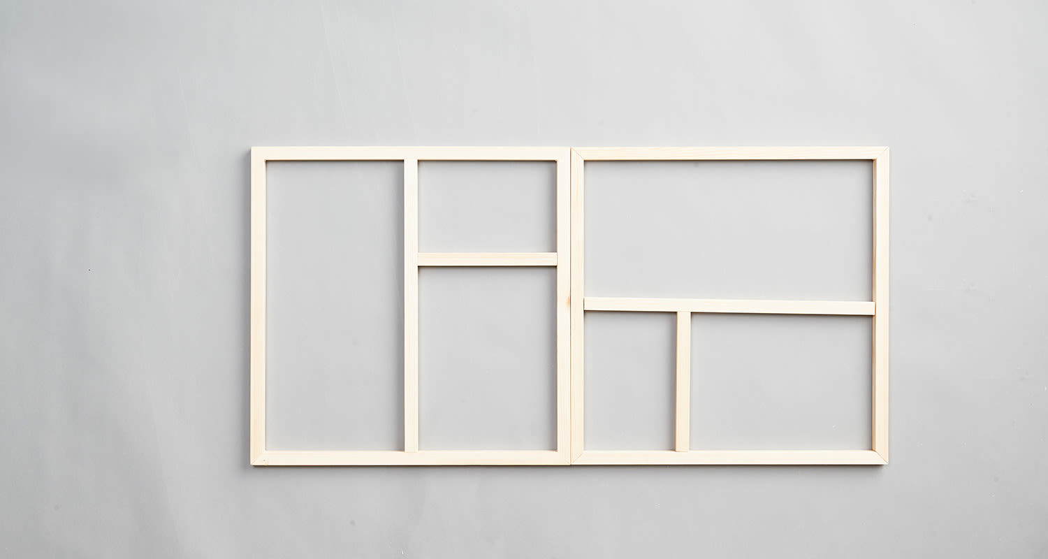 Vaaleat puukehykset epäsymmetrisillä lokeroilla harmaata seinäpintaa vasten