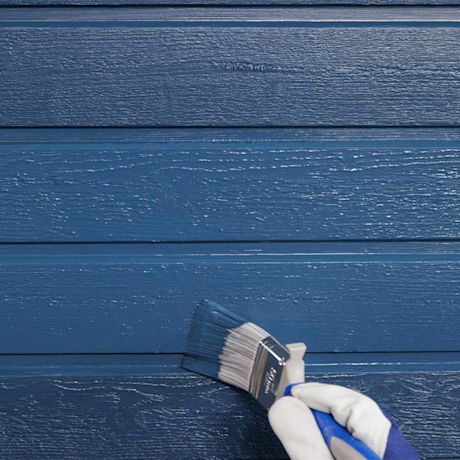 Pensseli valko-sinisessä hansikkaassa maalaa sinisiä vaakasuoria puulautoja