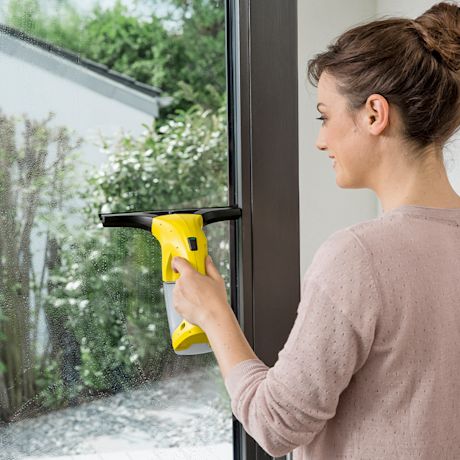 Nainen pesee ikkunoita Kärcherin ikkunapesurilla.