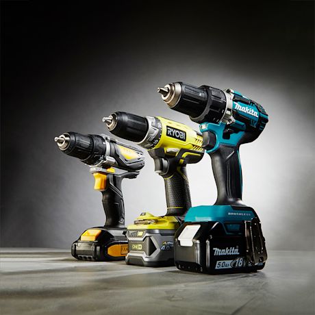 Kolme akkuruuvikonetta harmaata pintaa vasten: mustakeltainen, keltavihreä Ryobi ja sinimusta Makita