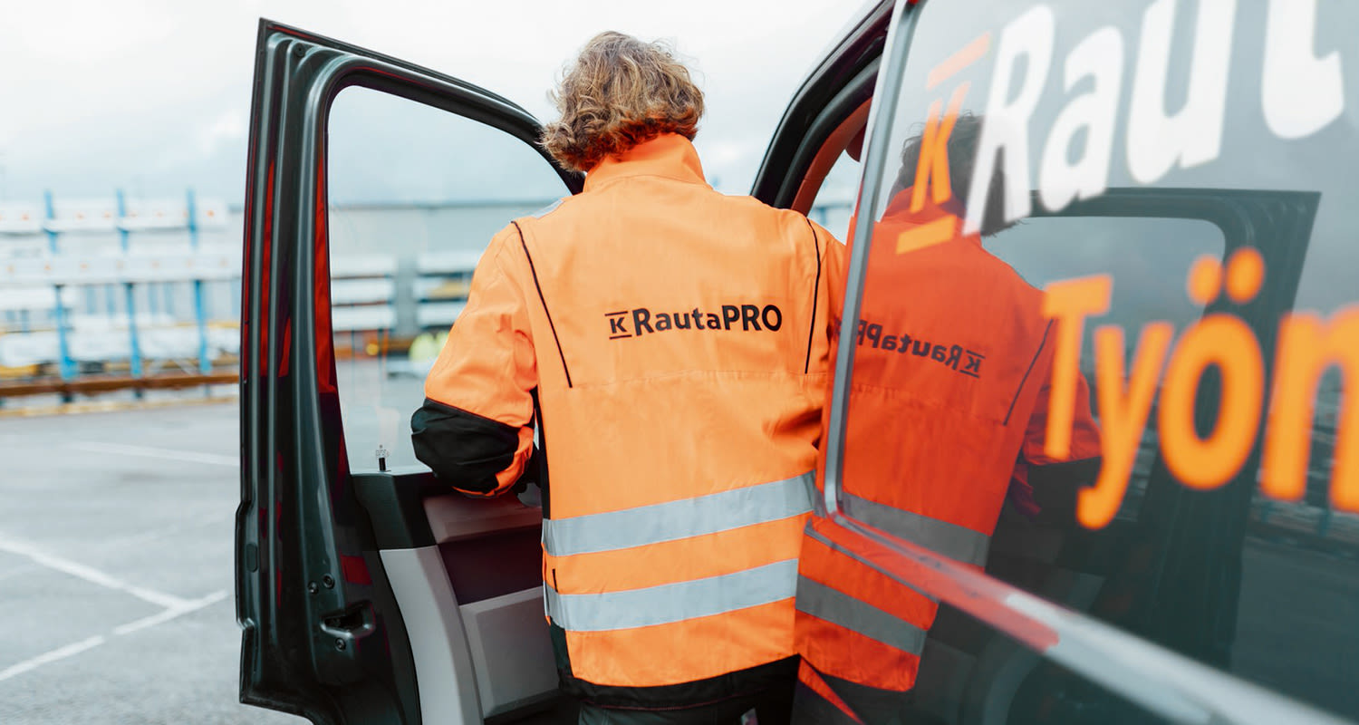 Työmies pakettiauton kanssa, painatus oranssissa huomiotyötakissa.