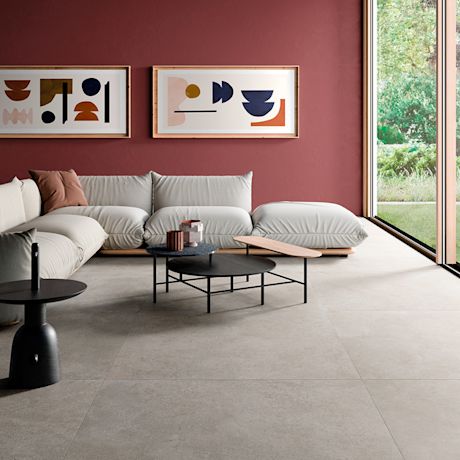 Olohuone punaisella seinällä, sohva, abstraktia taidetta, mustat pöydät ja ikkuna puutarhanäkymään.