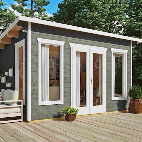 Vihreä-harmaa puumökki valkoisilla ikkunakehyksillä ja lasiovella puisella terassilla