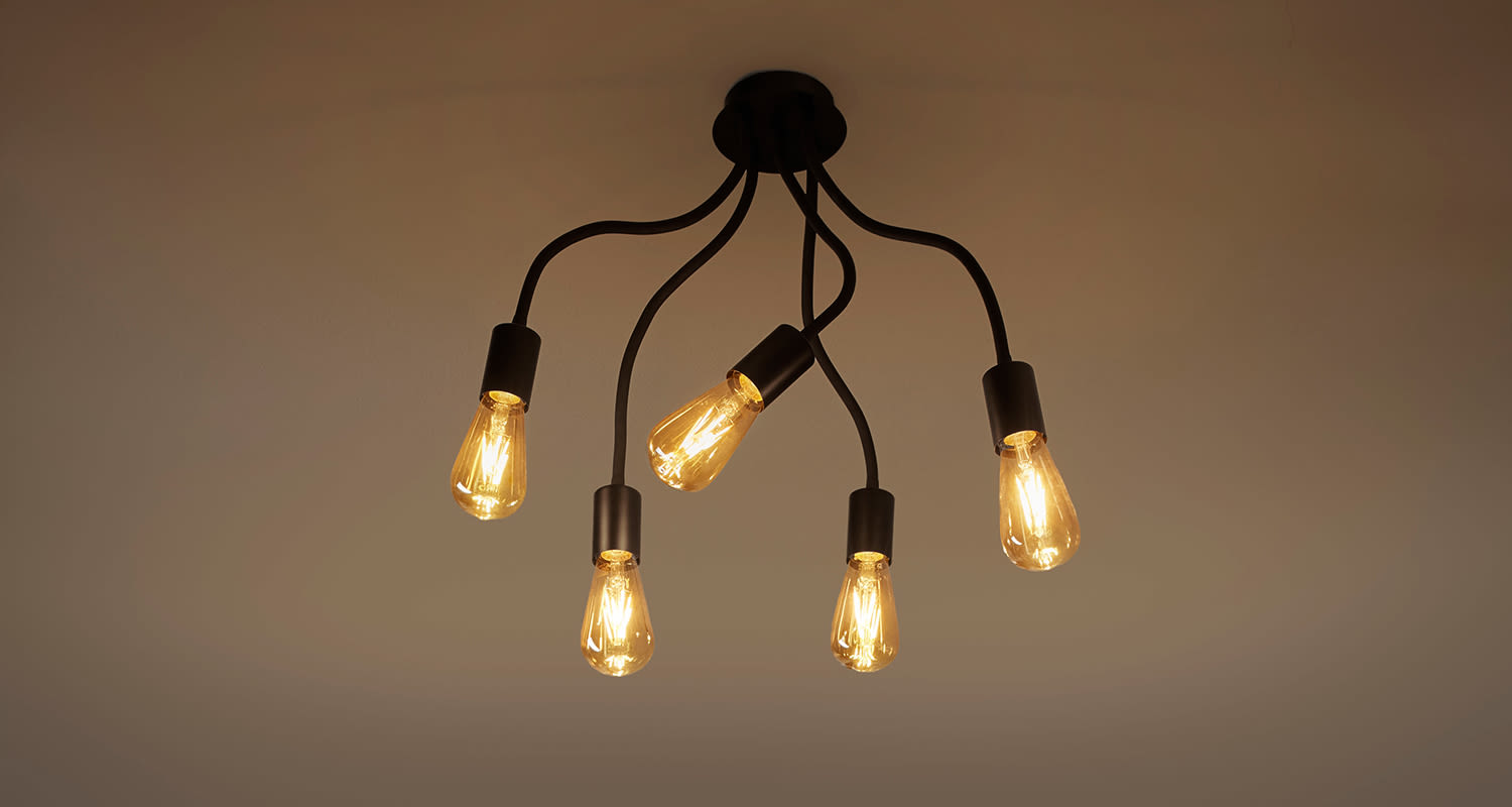Katosta roikkuva musta valaisin viidellä hehkulampulla ja lämpimällä keltaisella valolla