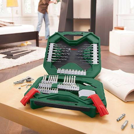 Vihreä Bosch-työkalulaukku auki pöydällä, poranteriä ja ruuvauskärkiä, taustalla huonekalun kasaaja.