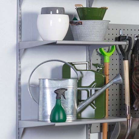 Harmaat ja vihreät puutarhatarvikkeet hyllyllä: kastelukannu, jerrykannu, suihkepullo ja lapioita