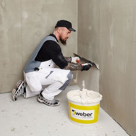 Työmies levittää Weberin käsikipsilaastia seinään, tuote myynnissä K-Raudassa