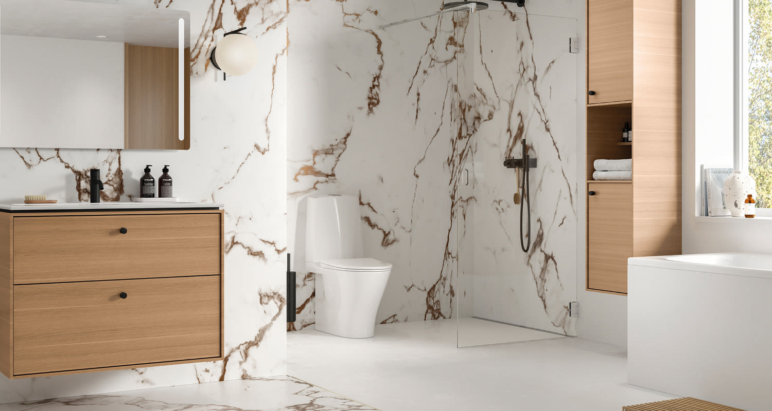 Moderni kylpyhuone valkoisilla marmoriseinillä, puukaapit, lasinen suihku ja valkoinen wc-istuin