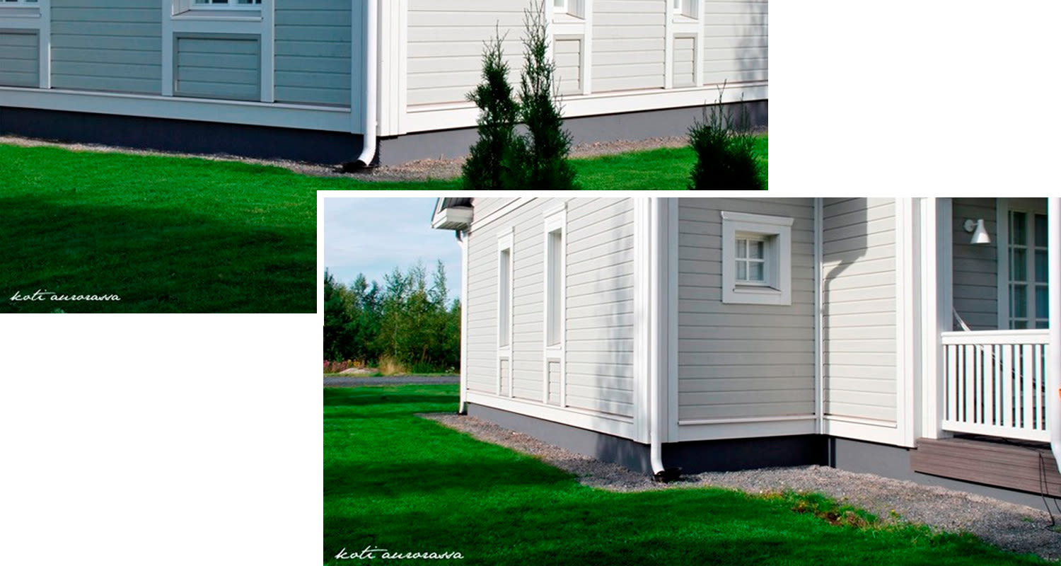 Vaaleanharmaan puutalon kulma, valkoinen räystäskouru, pienet kuusentaimet ja rehevä vihreä nurmikko