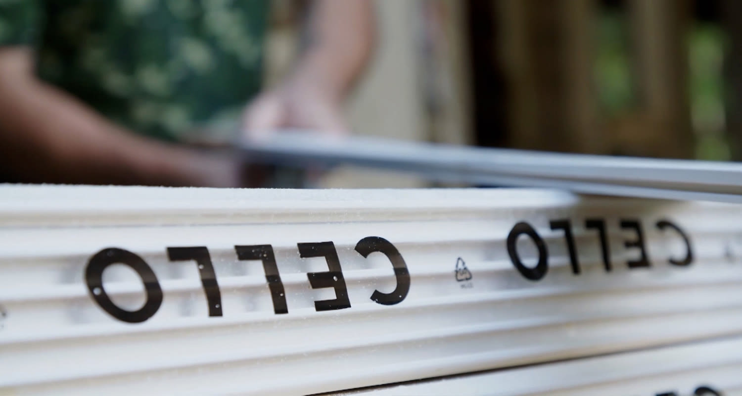 Pino valkoisia uritettuja muovilevyjä mustalla CELLO-logolla rakennustyömaalla