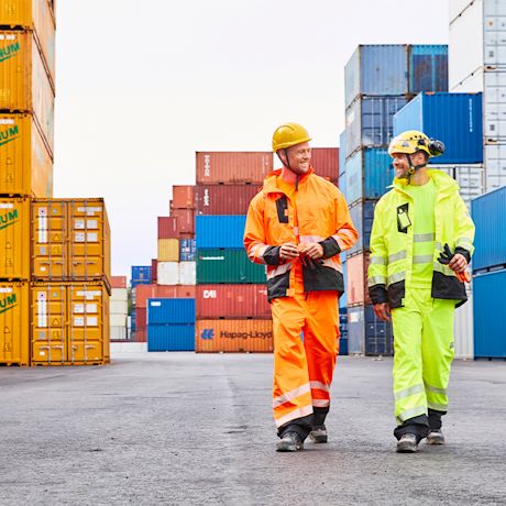 Kaksi rakennusmiestä Vuosaaren satamassa. Miehillä on yllä K-Raudann PROF Workwear -työvaatteet.