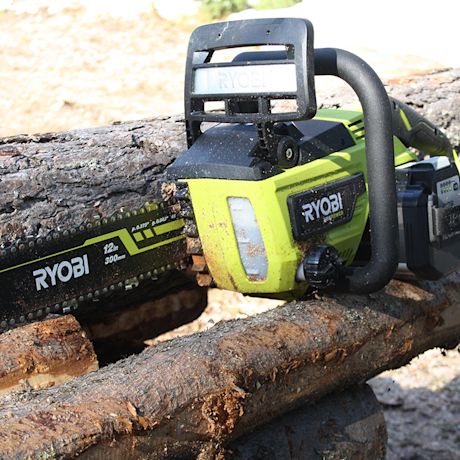 Ryobi-akkuketjusaha puunrunkojen päällä
