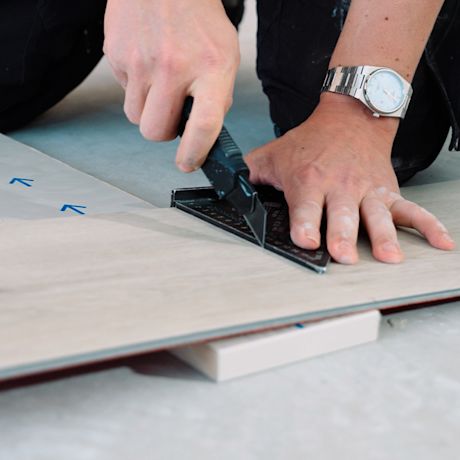 Vinyylilankun asennus: Mies leikkaa vinyylilankkua.