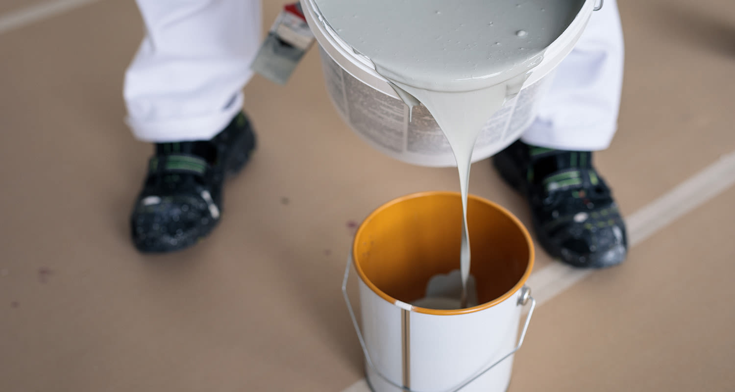 Maalari kaataa maalia pienempään purkkiin