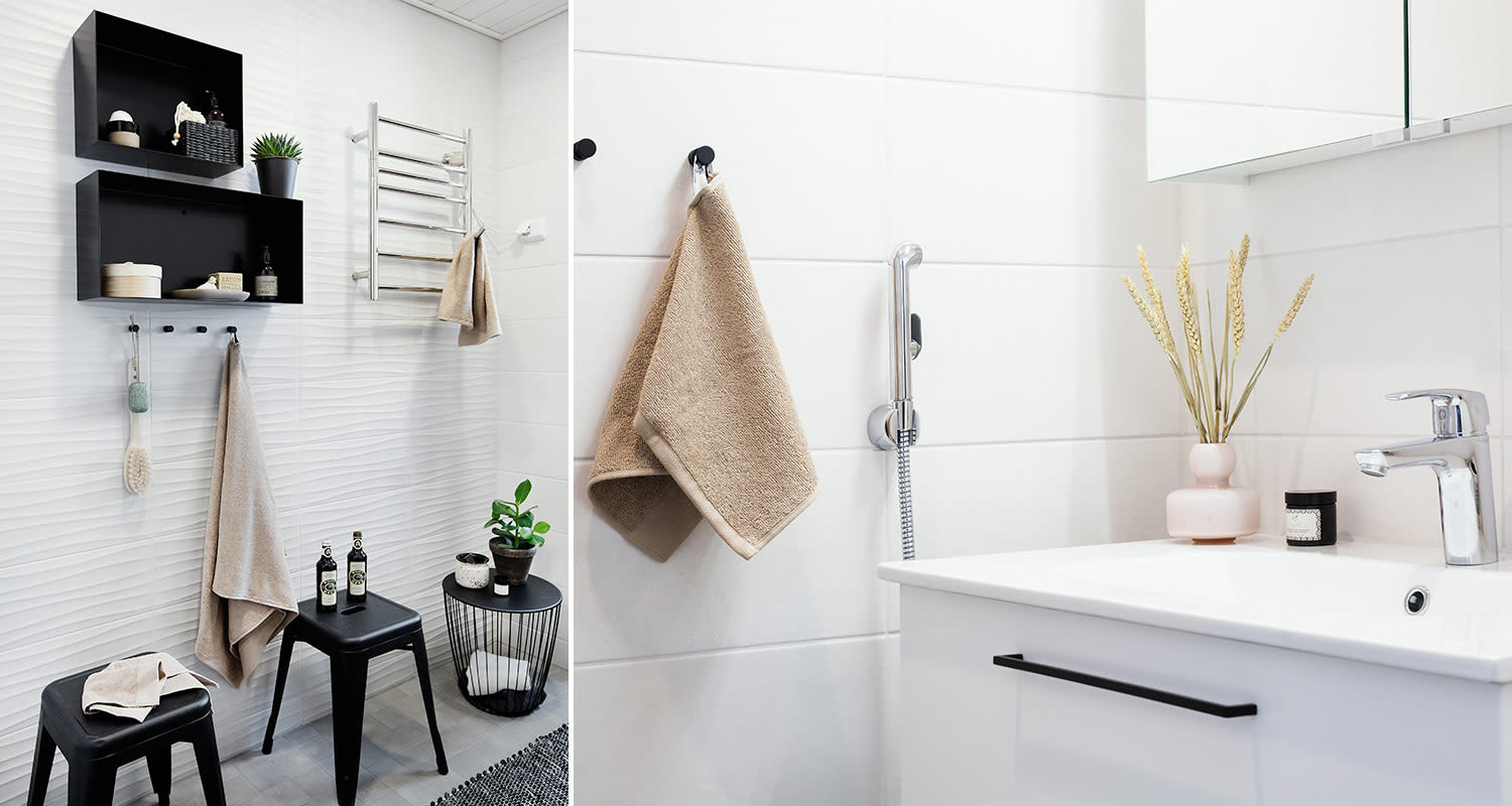 Kylpyhuone valkoisilla aaltoilevilla laatoilla ja mustilla tuoleilla ja hyllyillä