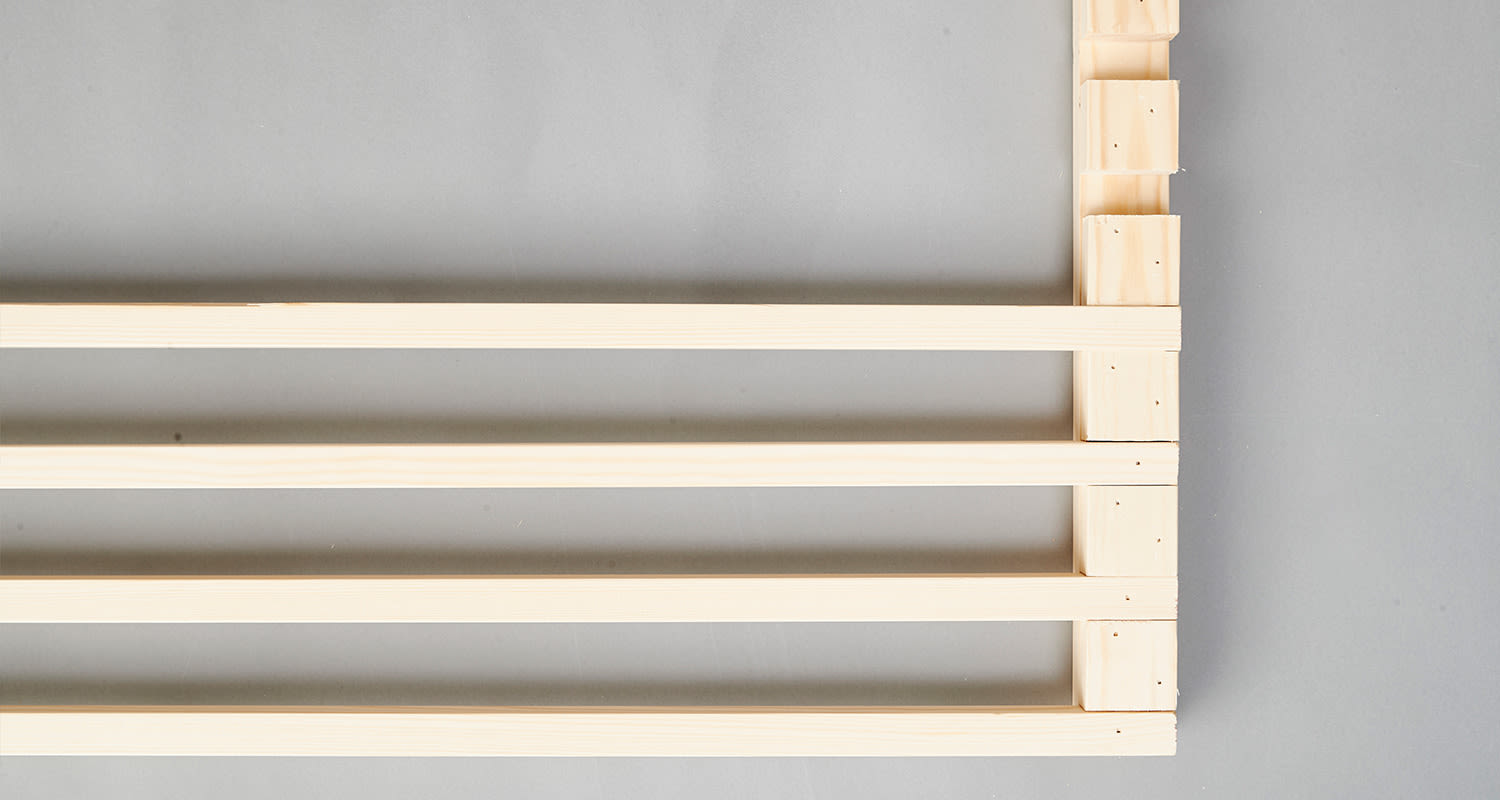 Vaaleat puulistat neljässä vaakarivissä harmaata pintaa vasten.