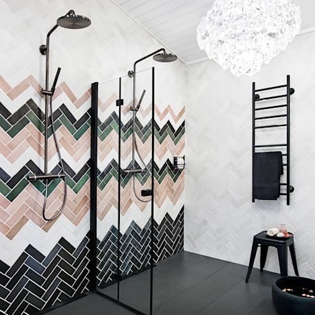 Moderni kylpyhuone, mustat sadesuihkut, pinkki-vihreä-musta kalanruotolaatta ja musta pyyheteline