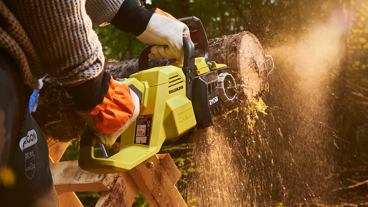 Mies sahaa Ryobin akkuketjusahalla puunrunkoa