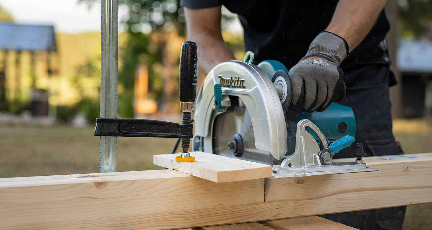 Modernin pergolan rakentaminen. Kuvassa runkopuiden sahaus.