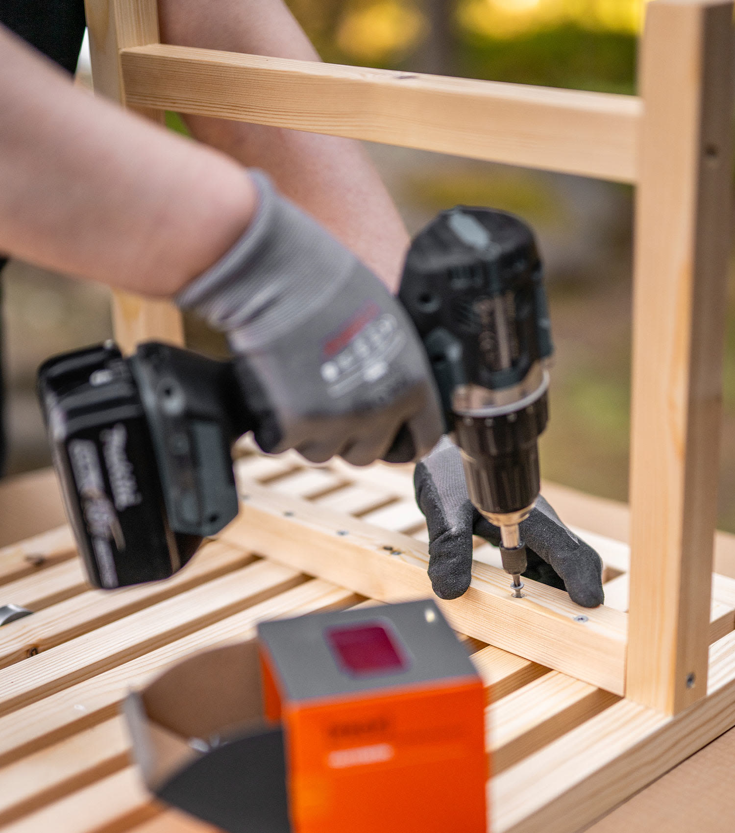 DIY: Sohvapöytä. Kuvassa diy-sohvapöytä valmistumassa. Tekijä kiinnittää osia yhteen.