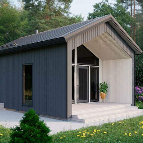 Musta-valkoinen moderni mökki kuistilla, nurmikolla voikukkia ja metsää takana