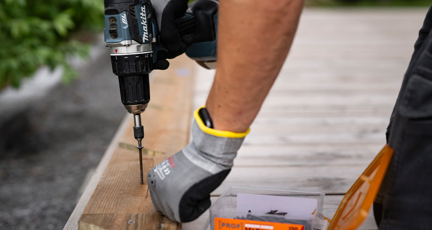 Tee itse terassikaide: Mies kiinnittää terassikaiteen alarunkopuuta terassiin