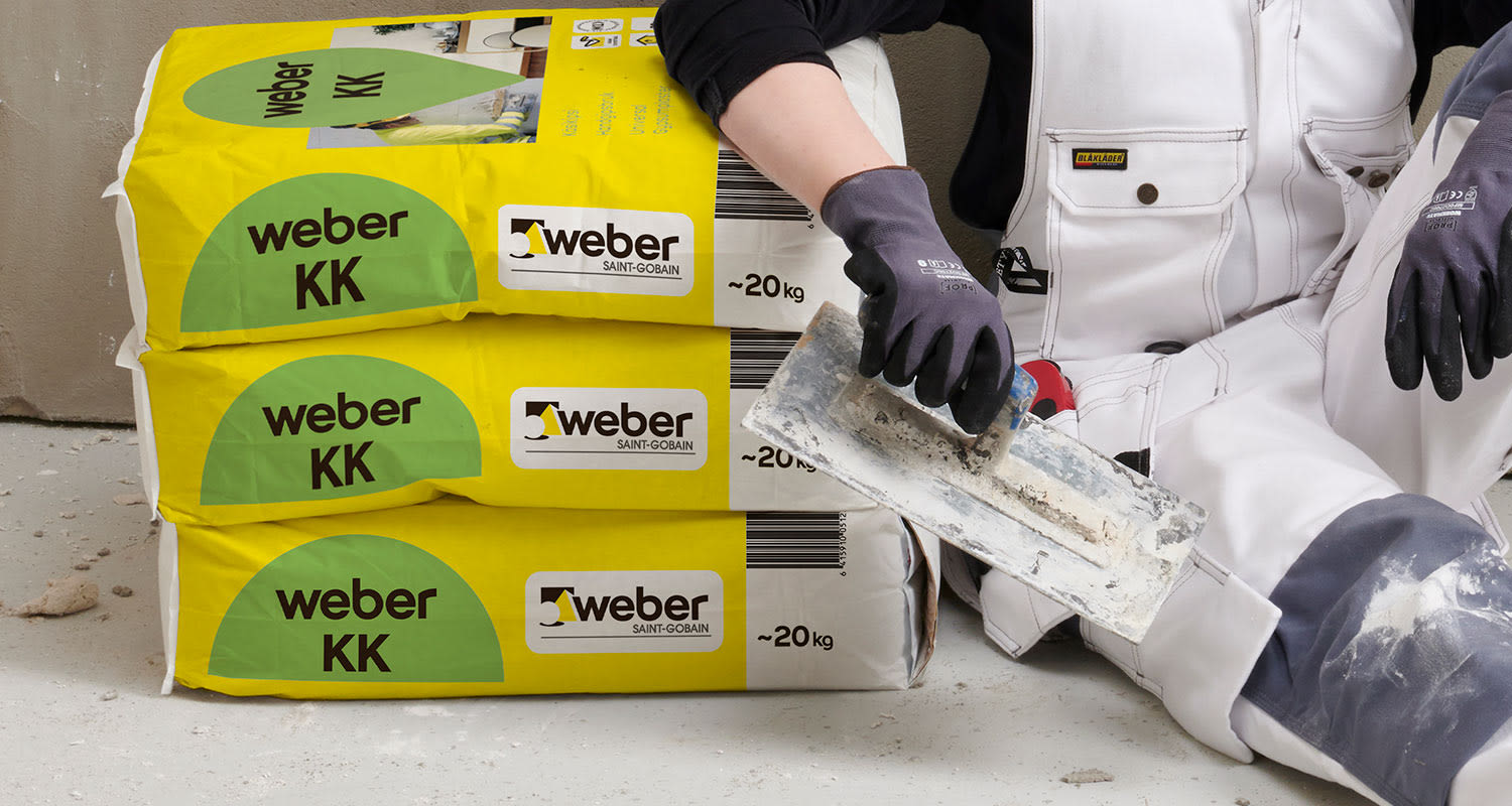 Weberin käsikipsilaastin pakkaukset ja ammattilainen säkkien vieressä
