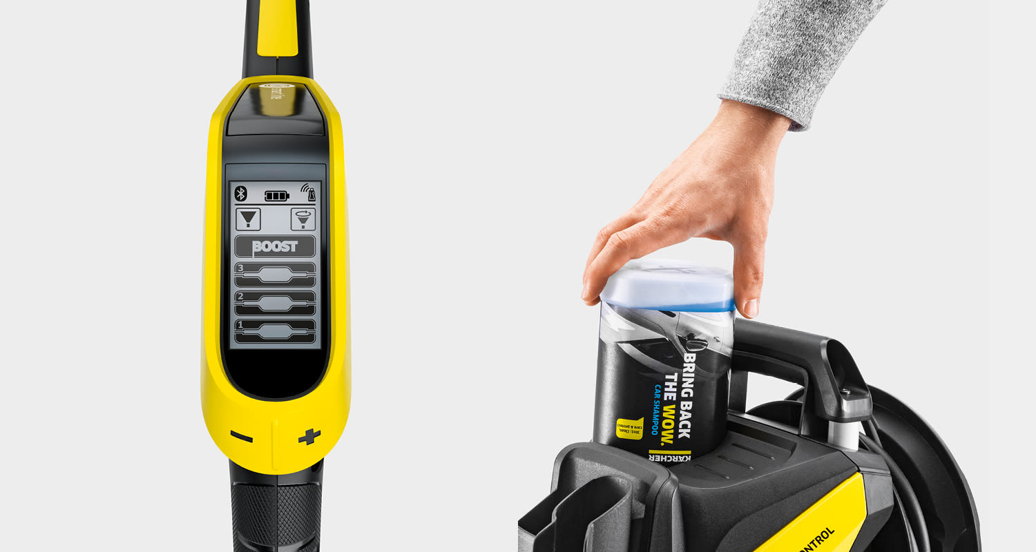 Keltamusta Kärcher-painepesuri diginäytöllä, käsi asettaa sinivalkoisen shampoopullon