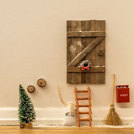 Tonttuovi valmiina kodin seinässä. Tonttuovi sekä kuusi, tikkaat, luuta sekä postilaatikko näkyy kuvassa.