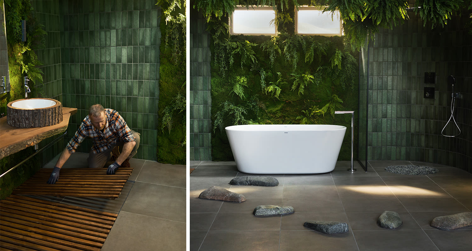 Mies asettaa puista ritilää kylpyhuoneen lattialle. Vieressä näkyy kylpyhuoneen lattiaan asennetut rantakivet.