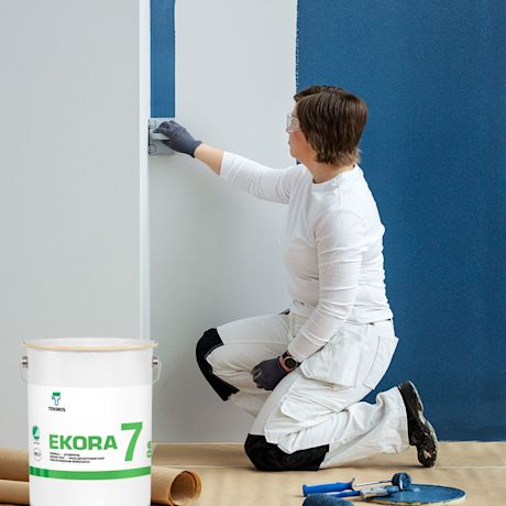 Maalari maalaa sisäseinää sinisellä maalilla, kuvassa Teknoksen Ekora 4 -sisämaalin pakkaus