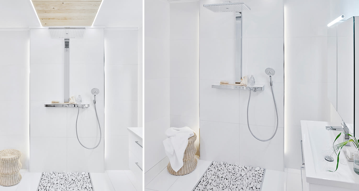 Minimalistinen valkoinen kylpyhuone, metallinen sadesuihku, kivimatta lattiassa ja rottinkikori.