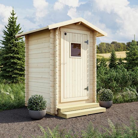 Vaalea puinen ulkorakennus pihalla, oven pieni ikkuna, ruukkuistutuksia ja metsää taustalla.