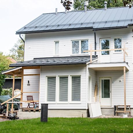 Valoinen suuri puuomakotitalo, julkisivun maalaus menossa