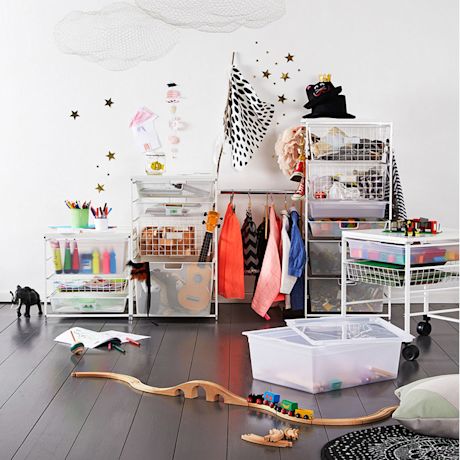 Leikkihuone, valkoiset säilytyskorit ja hyllyt, värikkäät takit, puinen junarata lattialla