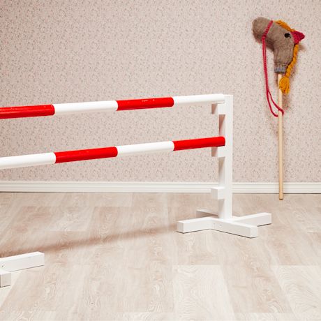 Lasten esterata sisätilassa kukkaseinän edessä: punavalkoiset puupalkit ja neulottu keppihevonen