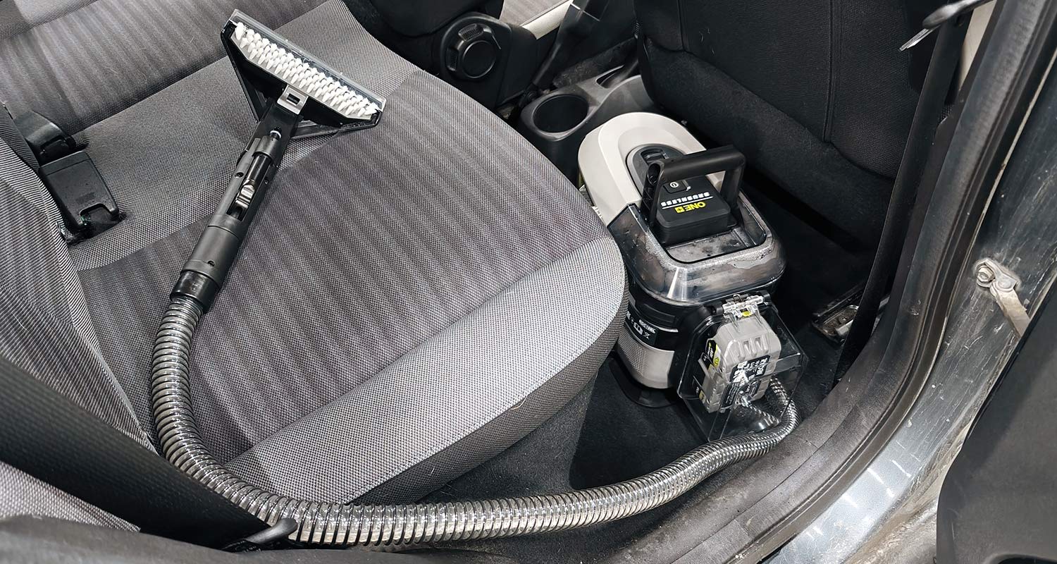 Ryobin tekstiilipesuri RDC18BL-0 18V ONE+ autossa, jossa on käynnissä istuimien pesu.